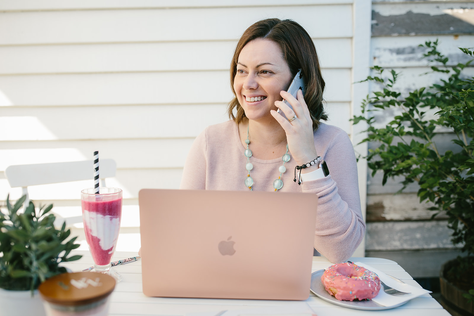 Gold Coast Bookkeeper for Woman in Business Lisa Turner sitting at a white desk beind laptop talking on mobile phone