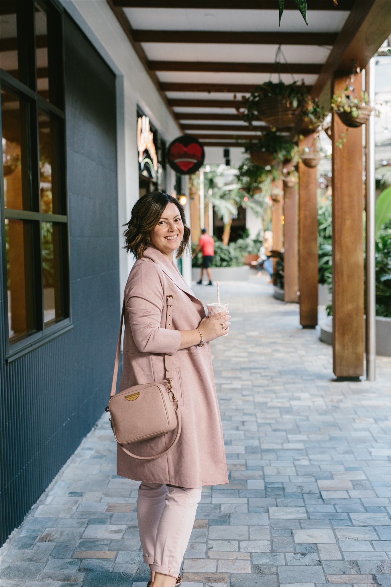Lisa Turner, Xero Bookkeeper for female led small business standing out the front of a café with a milkshake in hand wearing a pink coat and pink bag.